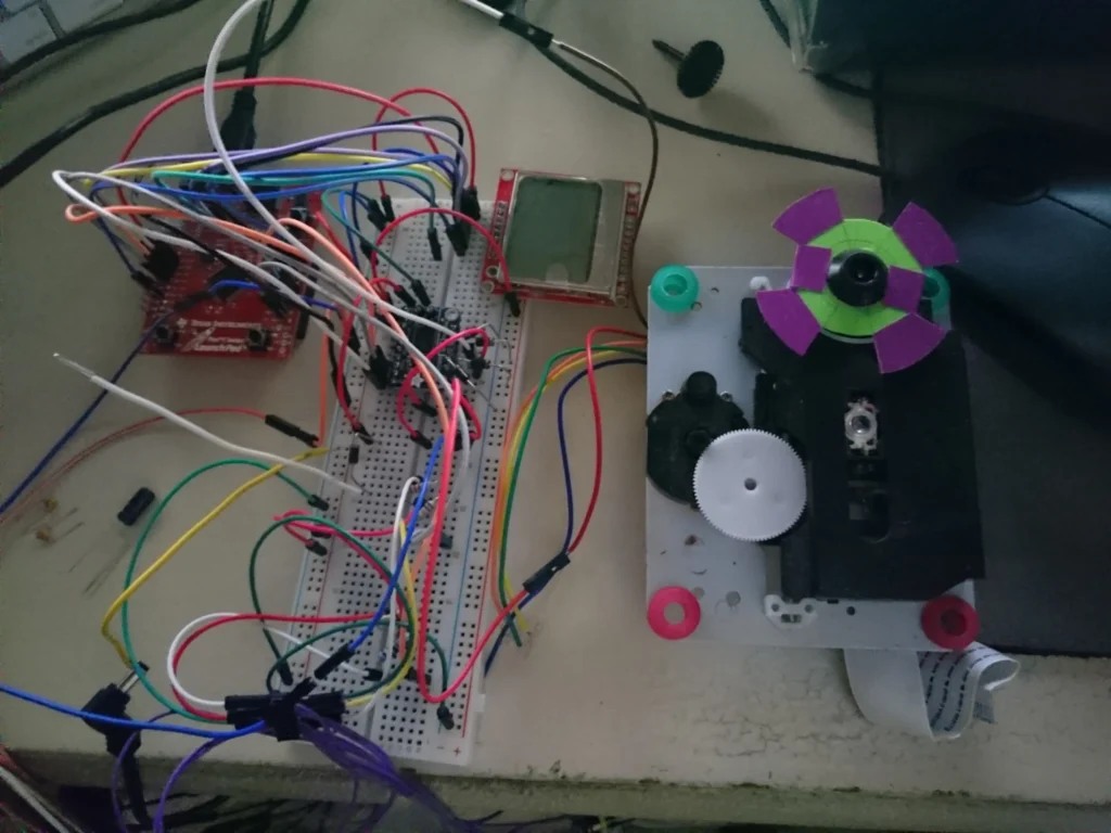 Arduino with LCD screen wired to breadboard and purple-green propeller motor assembly on workbench.