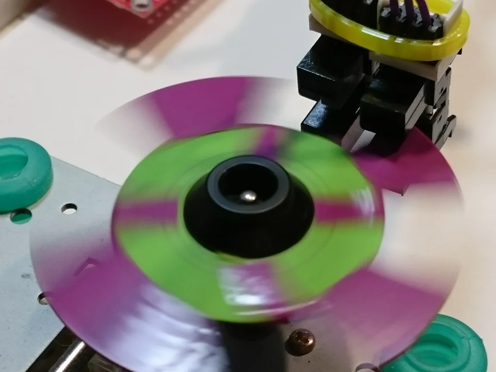 Spinning green and purple propeller on black motor mounted in LEGO and electronics setup.