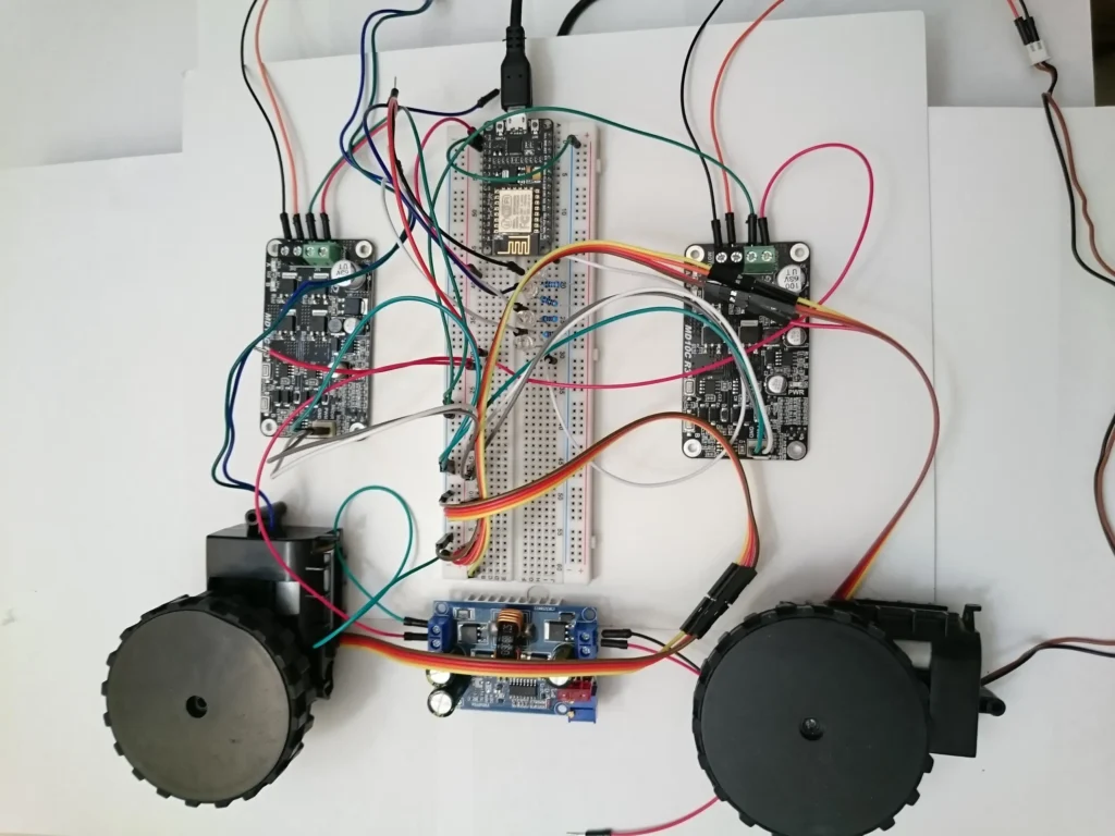ESP32 microcontroller, motor driver, and dual robot wheels wired on a breadboard.