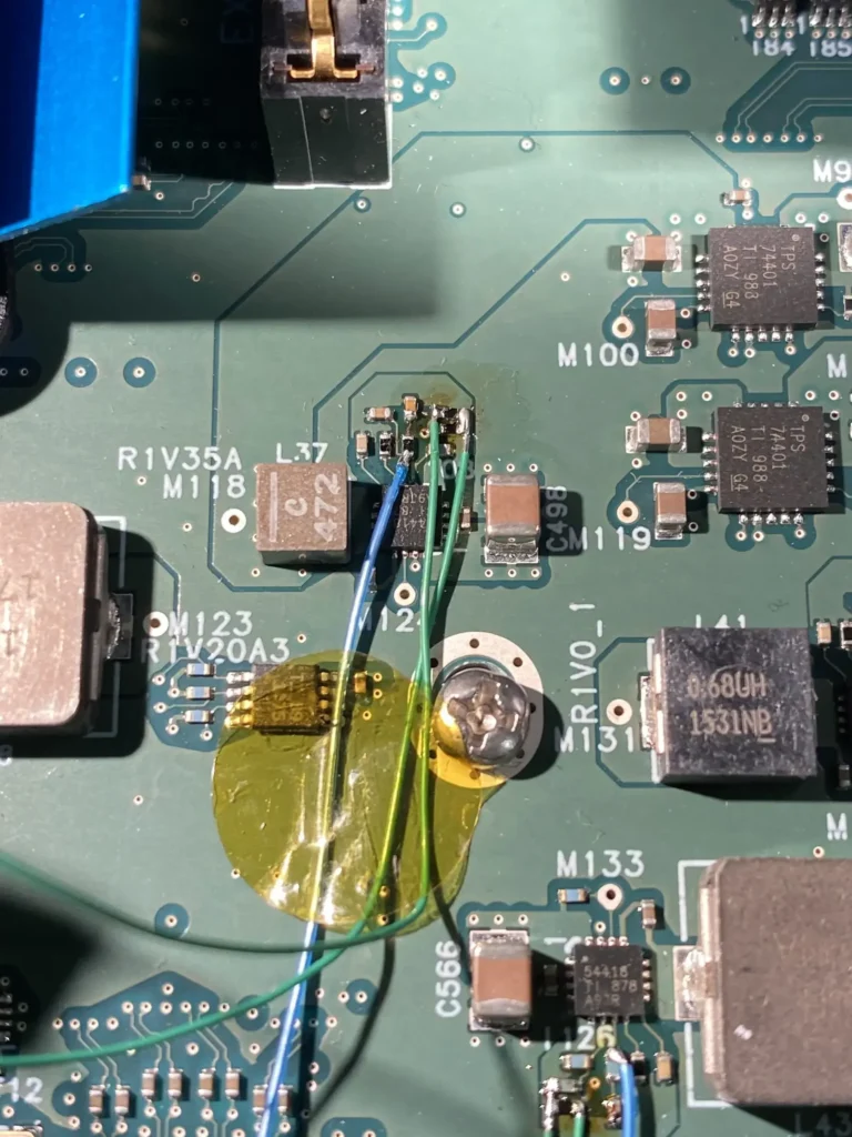 Close-up of a green PCB with labeled components, colored wires, and yellow Kapton tape.