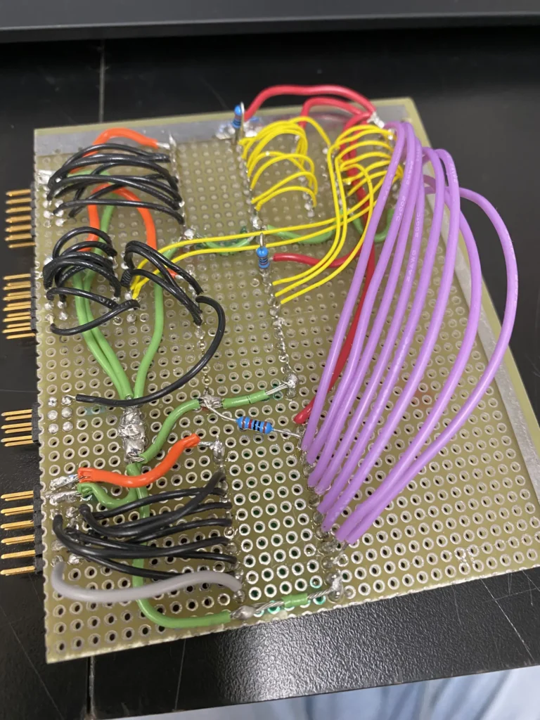 Color-coded wires and components soldered on a perforated prototyping board with pin headers.