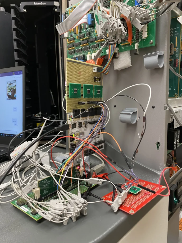 Close-up of tangled cables, circuit boards, and electronics rack including MicroScan hardware on a workbench.