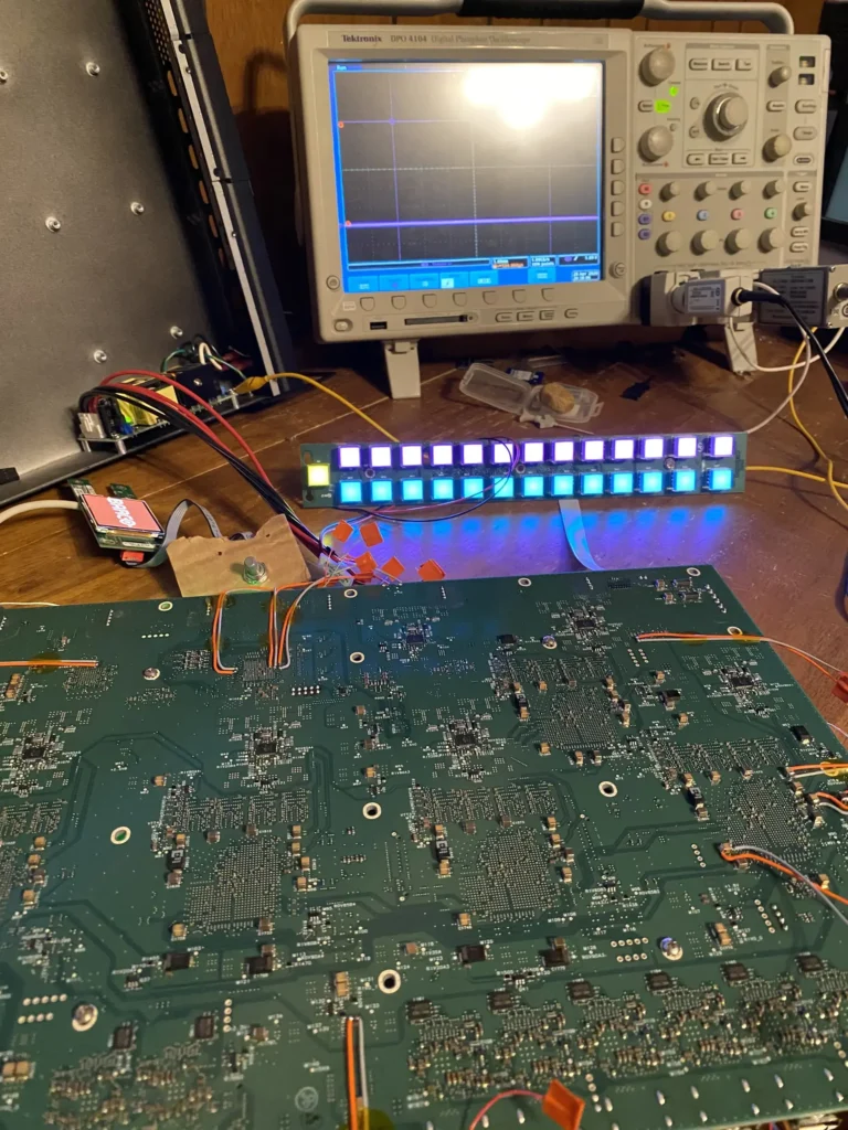 Tektronix oscilloscope displaying waveforms connected to a glowing LED matrix and green circuit board on workbench.