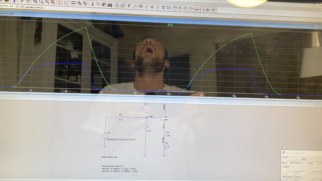 Oscilloscope displaying LED capacitive fade waveforms and circuit schematic with man's reflection.