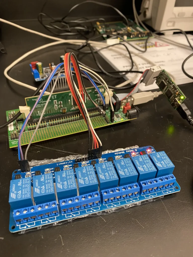 8-channel relay module wired to Raspberry Pi and Teensy microcontroller on workbench.