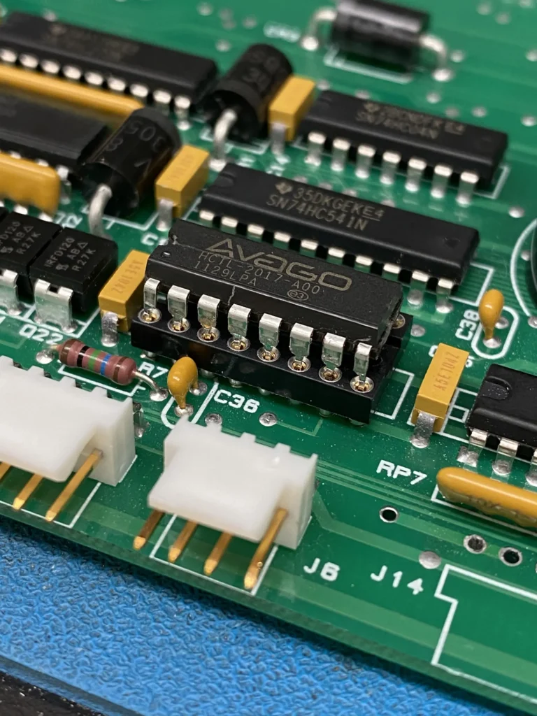 Close-up of a green PCB with Avago LED driver IC, resistors, capacitors, and white pin headers.