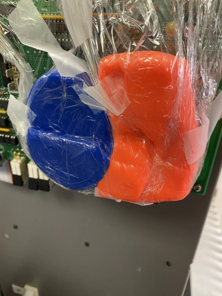 Blue and orange playdough in plastic bag on green circuit board.
